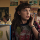 Eleven sits in a classroom with a scared look on her face.